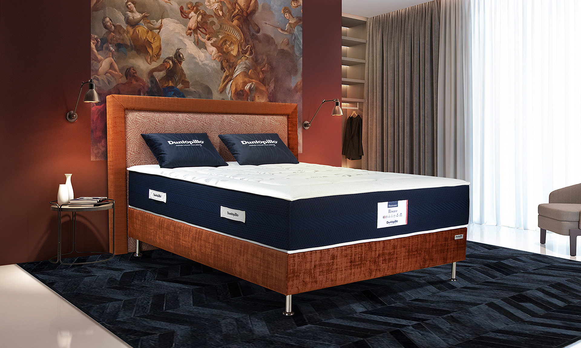 Un matelas avec âme ressorts et une plaque de mousse à mémoire de forme avec un sommier et tête de lit en velours orangé.